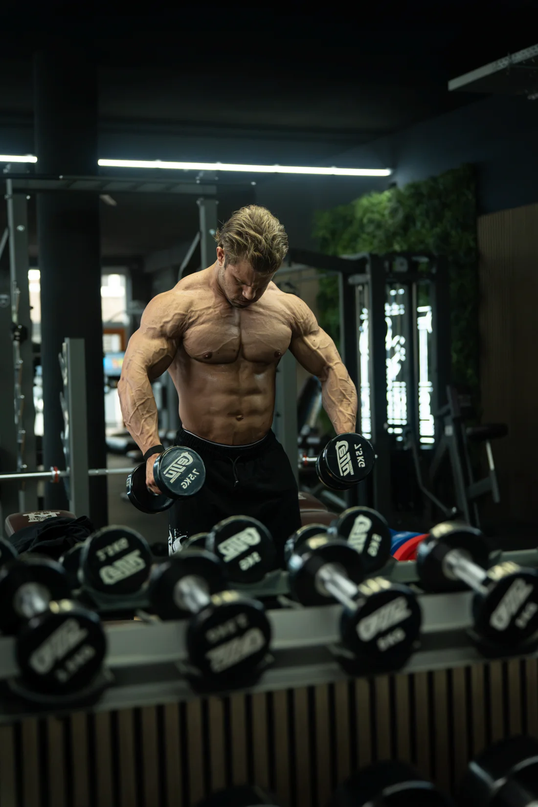 Atleet met dumbbells voor de spiegel
