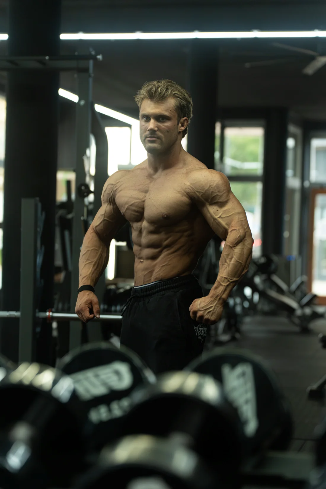 Atleet toont zijn fysiek naast de dumbbells