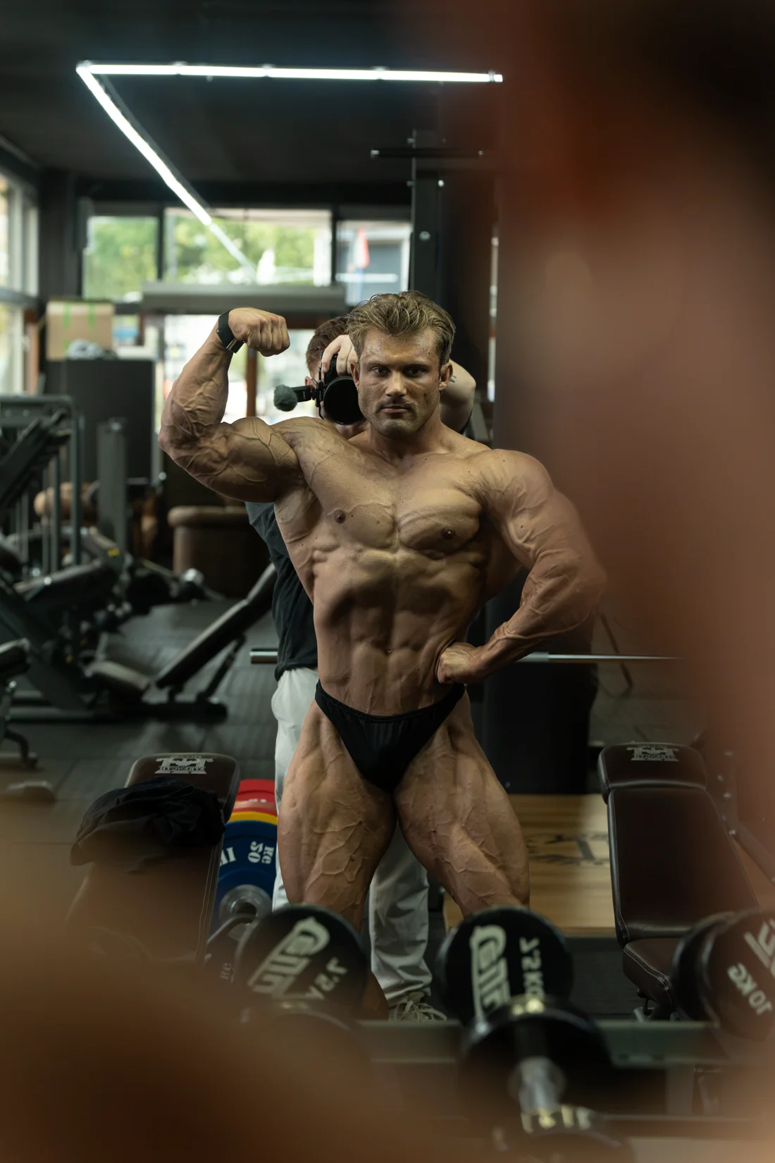 Bodybuilder poseert met gebogen armen voor de spiegel