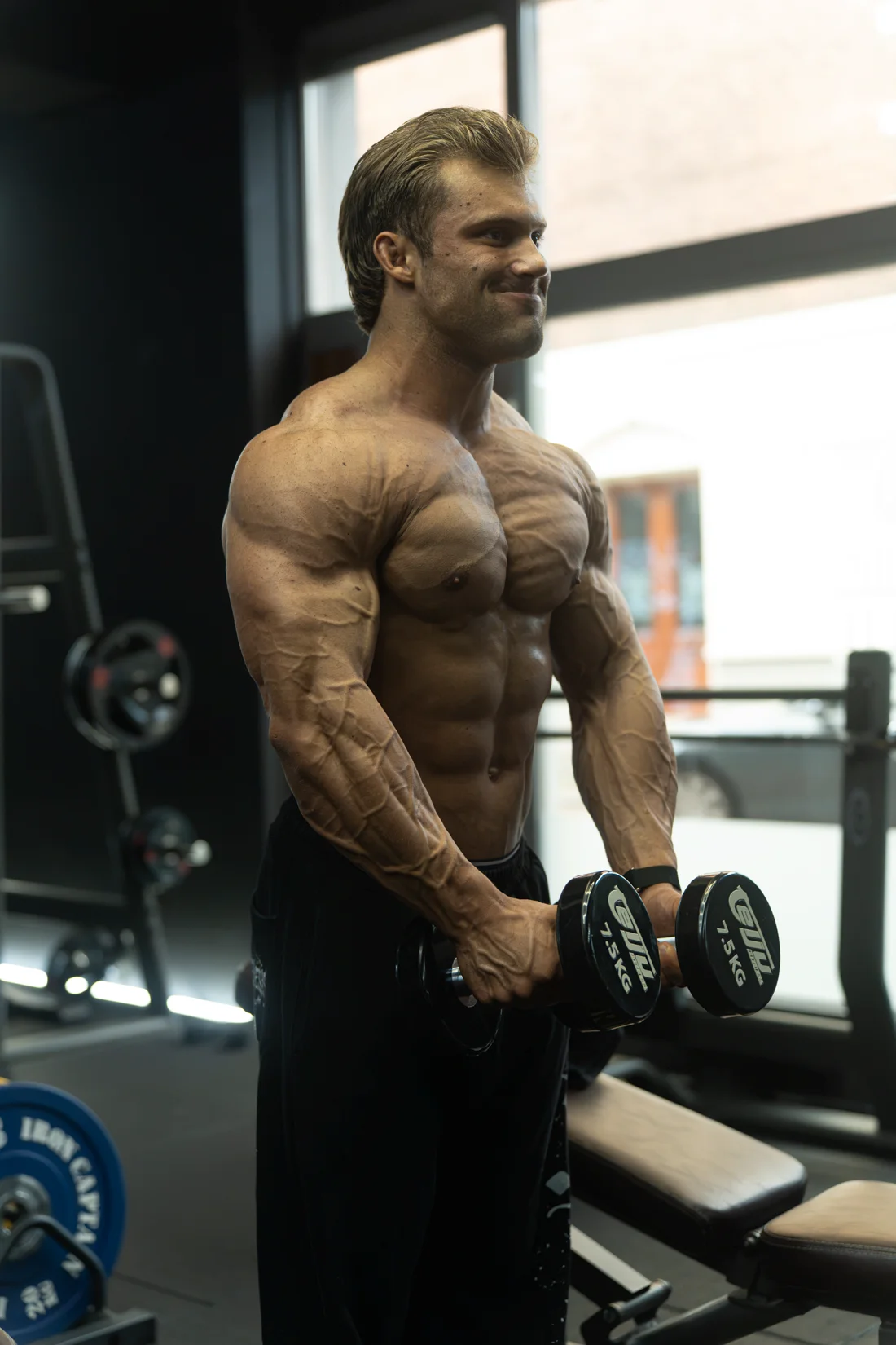 Atleet met dumbbells, gefotografeerd van opzij