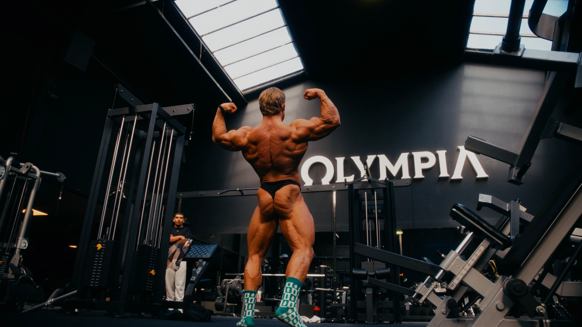 Bodybuilder toont een dubbele bicepspose van achteren in de gym